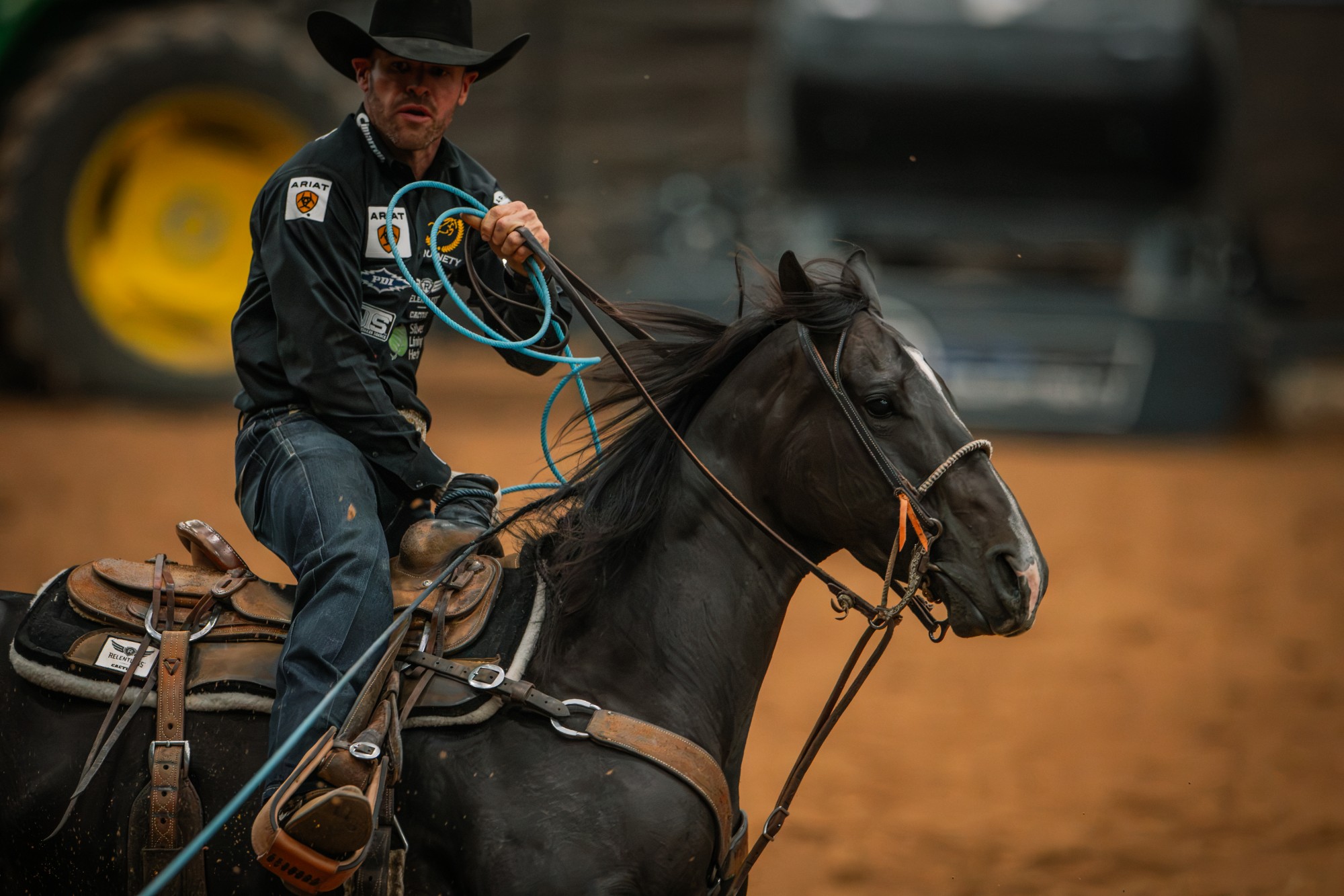 Miles Baker rides Fendiii, a black mare with a white blaze, with his rope coiled in his hand.