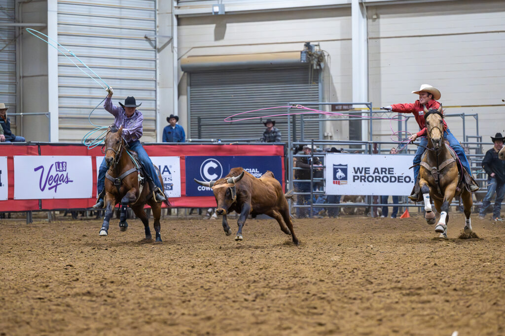 Header Clayton Van Aken and heeler Trey Yates swing their ropes behind a running steer.