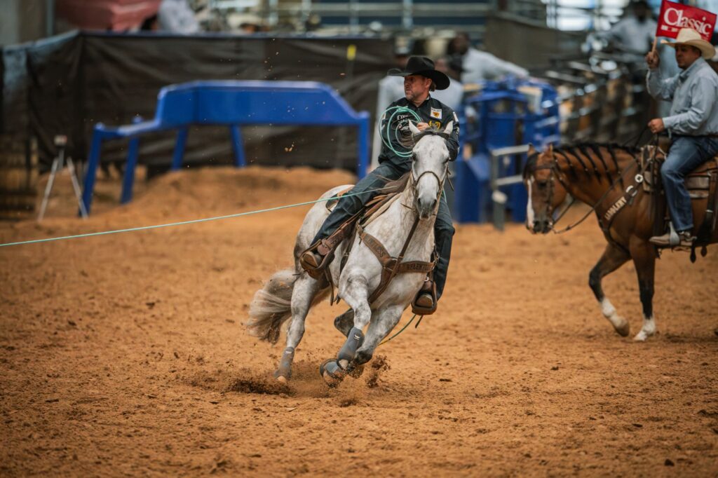 A header in a black hat turns a gray horse wearing a Relentless breast collar as a flagger rides alongside.