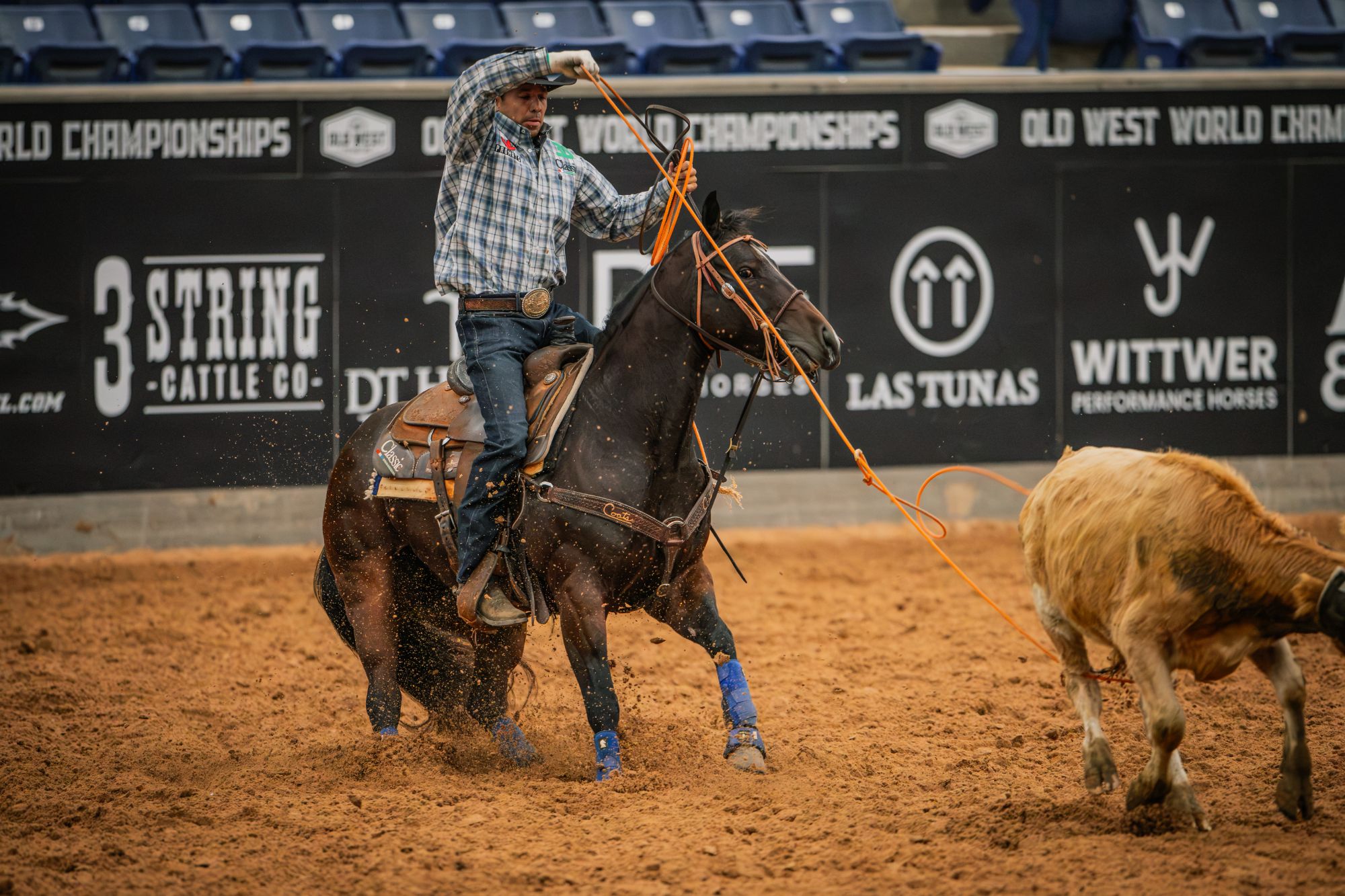 Kollin Von Ahn swings an orange heel loop on Reyzin Royals in front of Old West World Championships banners.